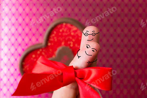 Preview: Love Concept With Two Fingers With Faces Over A Pink Patter Background