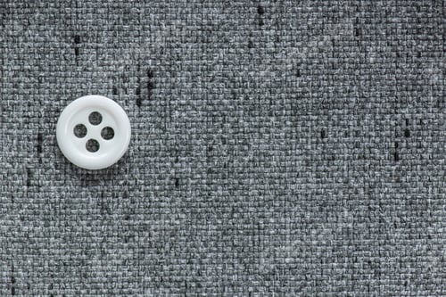 Preview: Clothes Sewing Button On A Gray Fabric Swatch Background