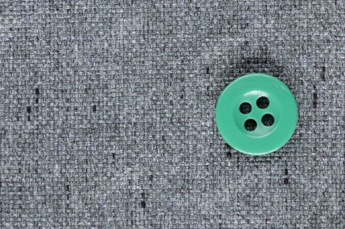 Preview: Clothes Sewing Button On A Gray Fabric Swatch Background