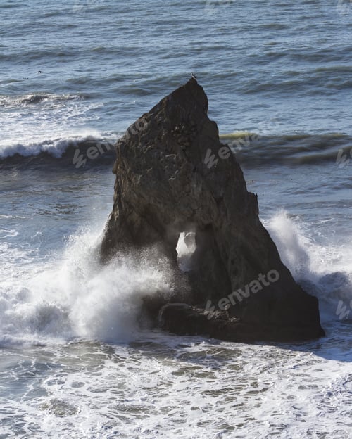 Preview: Powerful Waves Crashing Against A Large Rock With A Hole In The Middle