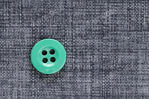 Preview: Clothes Sewing Button On A Gray Fabric Swatch Background