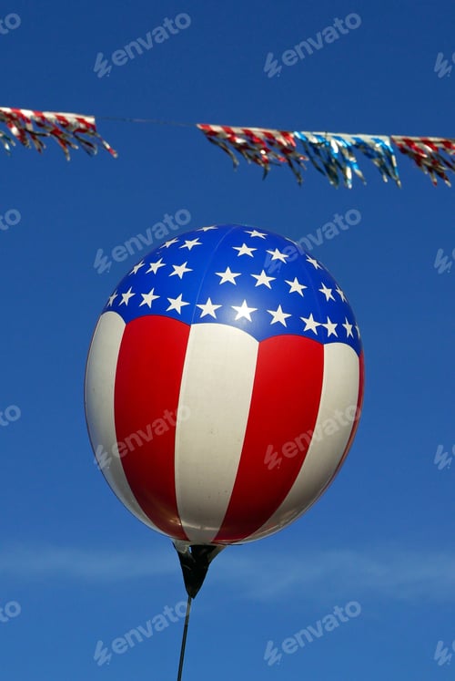 Preview: Balloon With An American Flag Motif Flying Against Blue Sky With Flag Flying In The Background