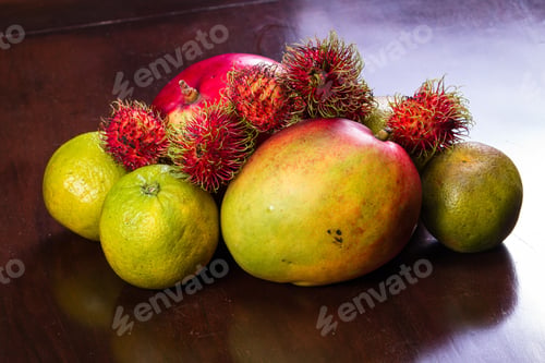 Preview: Tropical Fruit On A Kitchen Table Including Mangoes, Juicing Oranges And Colorful Rambutan