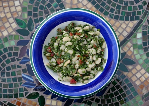 Preview: Salad With White Beans And Herbs On A Plate With Blue And Green Rim Seen From Above On A Table With