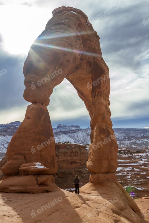 Preview: Delicate Arch In The Winter With A Hiker Standing At The Base Of To Show A Size Perspective Of This
