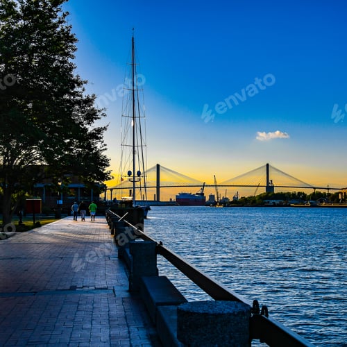 Preview: The Suspension Bridge And Anchored Sailboats In Savannah, Georgia From The River Walk With Tourists