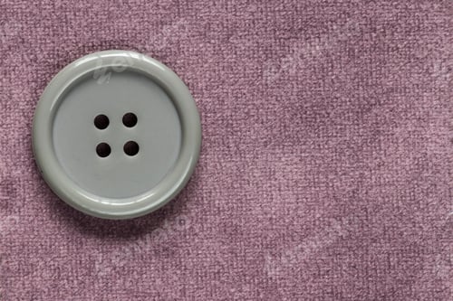 Preview: Clothes Sewing Button On A Purple Fabric Swatch Background