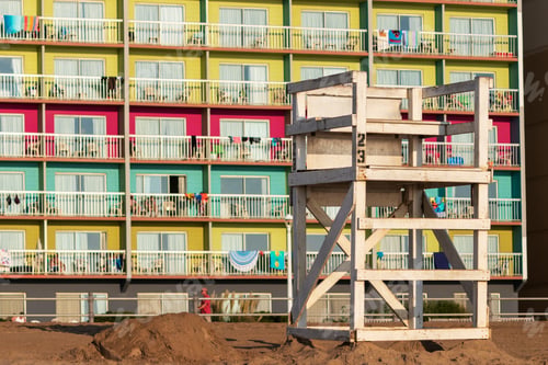 Preview: Empty Lifeguard Chair On The Beach Early In The Morning With The Colorful Balconies Of A Beachfront