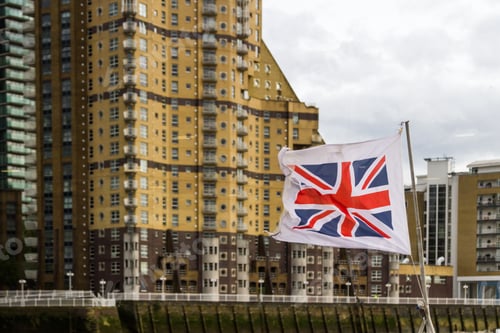 Preview: London - September 06 2019: Union Jack Flag Blowing In The Wind With Apartment Buildings In The