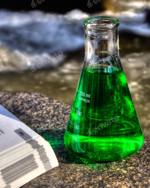 Preview: A Laboratory Flask And A Text Book Beside A Mountain Stream Suggesting Eco Science. This Is An Hdr