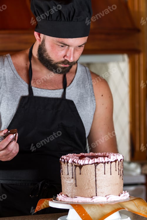 Preview: Male Baker Decorating A Chocolate Birthday Cake With Strawberry Moose Frosting And Dark Chocolate