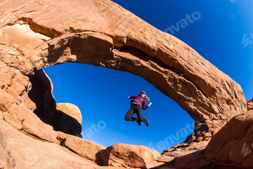 Preview: Woman In A Celebratory Jump At The Base Of North Window In Arches National Park
