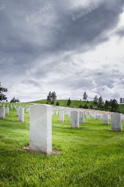 Preview: Rows Of Tombstones In A Military Graveyard With Bright Green Spring Grass And Dramatic Storm Clouds