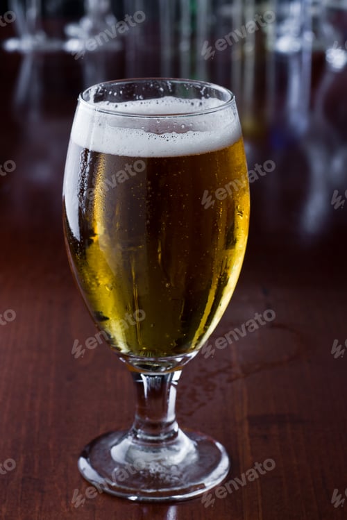 Preview: Golden Beer Poured In To A Chalice On A Busy Bar Top With A Shallow Depth Of Field Showing Lights