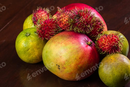 Preview: Tropical Fruit On A Kitchen Table Including Mangoes, Juicing Oranges And Colorful Rambutan