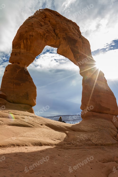 Preview: Delicate Arch In The Winter With A Hiker Laying At The Base Of To Show A Size Perspective Of This