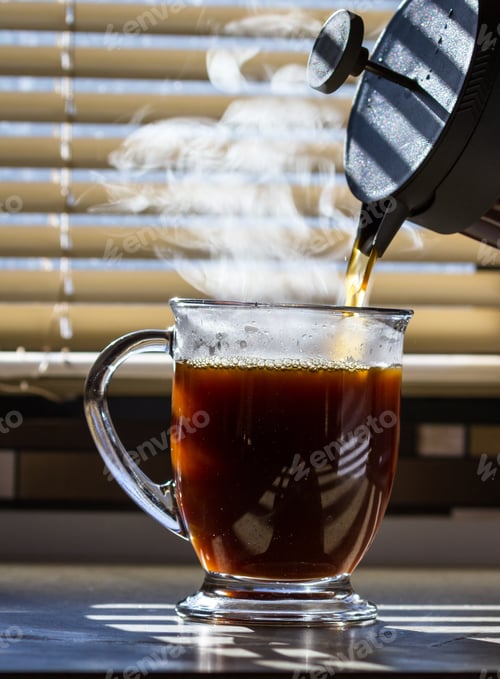 Preview: Close Up Of A Fresh Steaming Cup Of Coffee Served Indoors With Blinds Allowing Enough Light To