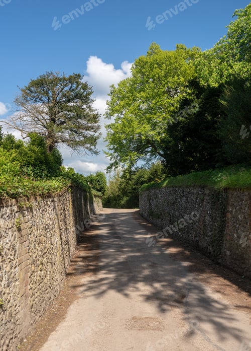 Preview: Narrow Road With Flint Stone Walls Leads Down To Forest Or Wood