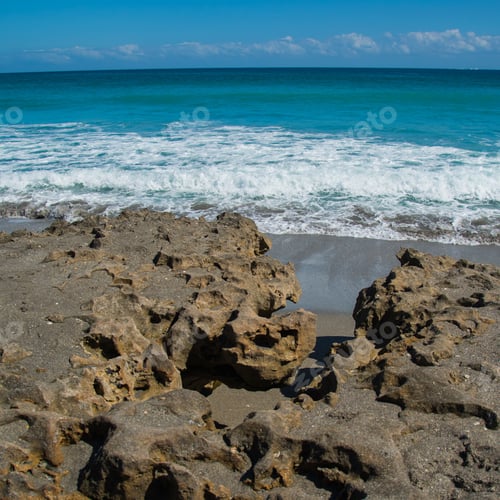 Preview: Ocean Waves As They Roll Toward The Rocks On A Florida Beach On A Sunny Day With A Backgrounds Of