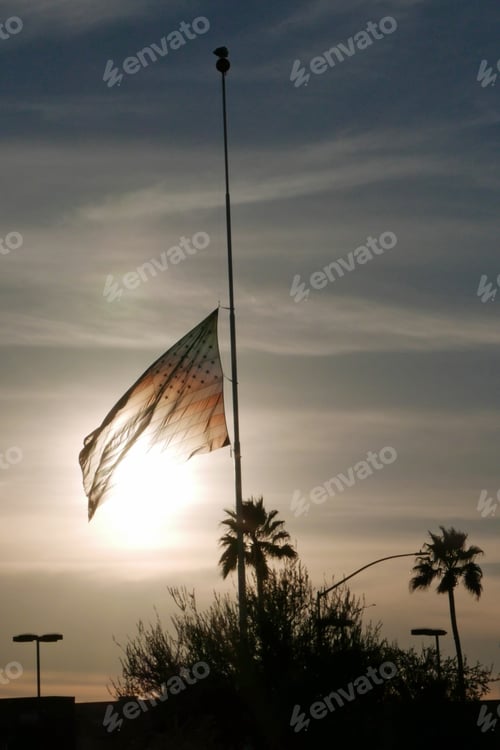Preview: American Flag Flying At Half Mast Against The Evening Sun