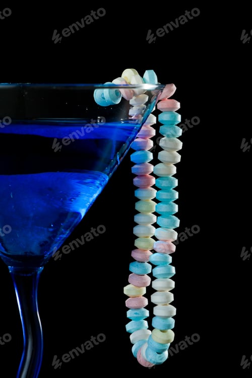 Preview: Blue Cocktail Isolated On A Black Background With A Candy Necklace Wrapped Around It