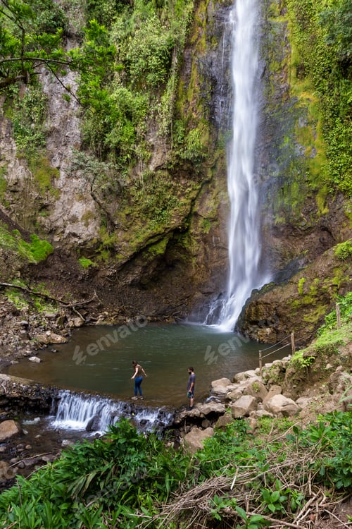 Preview: Young Couple Standing Near A Tall Waterfall Admiring This Natural Beauty In Costa Rica