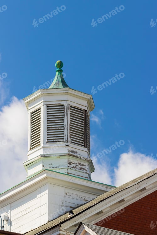 Preview: Vented Wooden Cupola On Top Of An Old Brick Building Against A Blue Sky