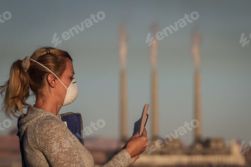 Preview: Concept Image Of A Woman Sitting Reading A Book Wearing A Mask With A Coal Power Plant And Dirty