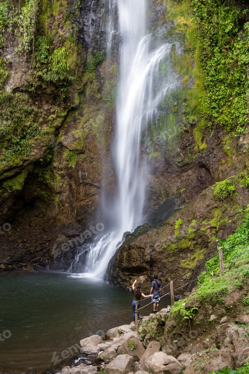 Preview: Young Couple Standing Near A Tall Waterfall Admiring This Natural Beauty In Costa Rica