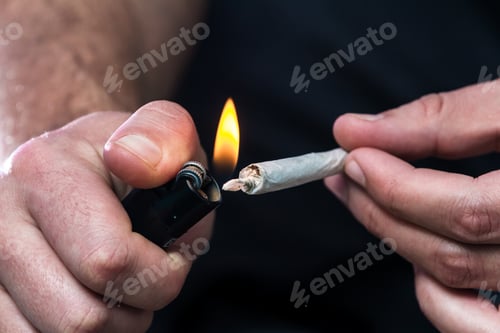 Preview: Close Up Of A A Mans Hands With A Rolled Marijuana Joint And Lighting It With A Lighter