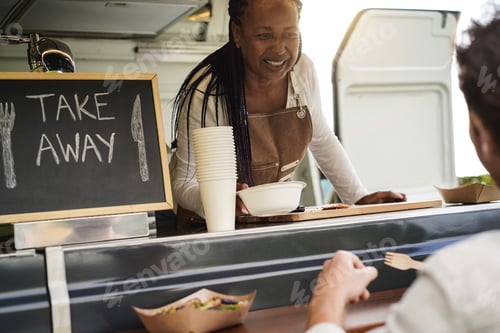 Preview: African American Senior Woman Serving Take Away Food Inside Food Truck - Soft Focus On Female Face