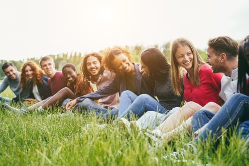 Preview: Multiethnic Friends Having Fun Sitting On Grass Outdoor - Focus On Right Girl Face