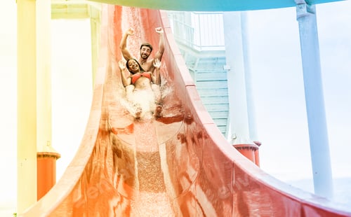 Preview: Young Couple Splashing Into A Waterslide At Aqua Park For Summer Vacation - Multiracial People