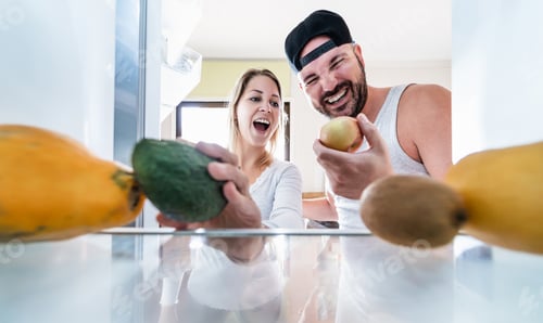 Preview: Young Couple Open The Fridge At Home While Choosing Organic Fruits For Fresh Smoothie - Happy
