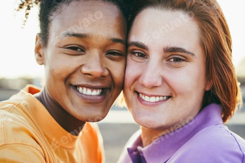 Preview: Multiracial Women Gay Couple Smiling On Camera Outdoor - Main Focus On African Girl Left Eye