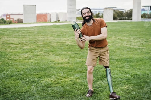 Preview: Young Man Holding A Part Of His Prosthetic Leg At City Park - Focus On Hands Holding Prosthesis