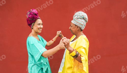 Preview: Happy African Mother And Daughter Dancing Together While Wearing Traditional Clothes - Motherhood