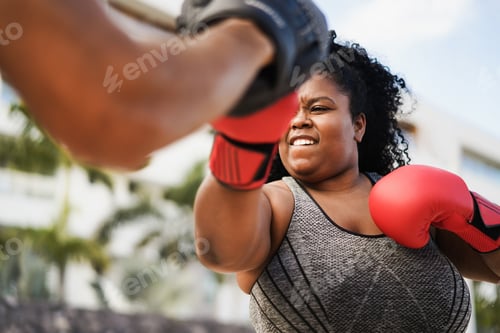 Preview: African Curvy Woman And Personal Trainer Doing Boxing Workout Session Outdoor - Focus On Her Face