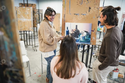 Preview: Mature Teacher Working With Art Students During Painting Class At School - Focus On Woman Face