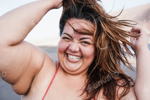 Preview: Curvy Woman Smiling On Camera Wearing Bikini With Beach In Background - Focus On Face
