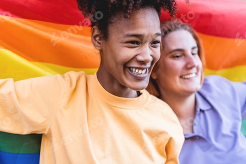 Preview: Happy Women Gay Couple Holding Rainbow Flag Outdoor - Focus On African Girl Face