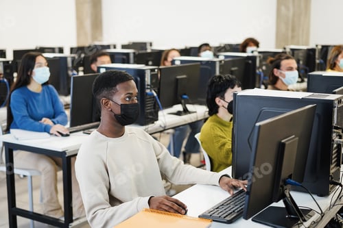 Preview: Multiracial Young Students Using Computers Inside Class Room Wearing Safety Masks During