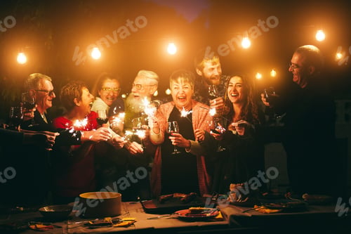 Preview: Happy Family Celebrating With Sparkler Fireworks On New Year'S Eve - Focus On Left Glasses