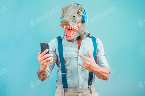 Preview: Crazy Tattooed Man With T-Rex Mask Using Smartphone While Listening Music - Crazy Senior Male