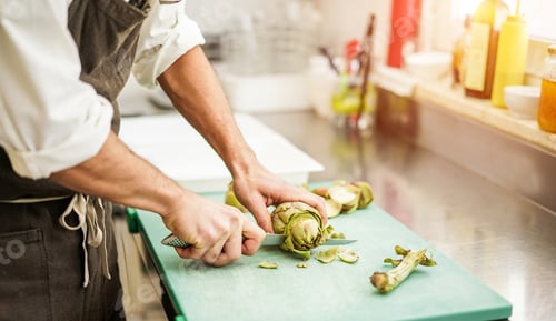 Preview: Chef Cutting Artichokes For Dinner Preparation - Man Cooking Inside Restaurant Kitchen - Focus On