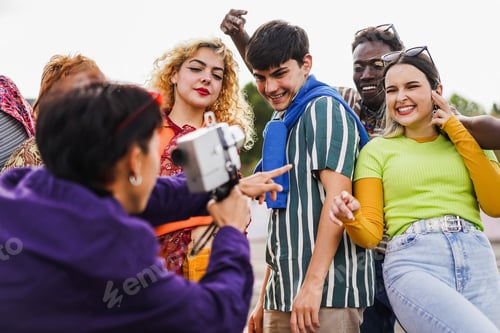 Preview: Young Diverse People Having Fun With Old Vintage Video Camera Outdoor - Focus On Left Girl Face