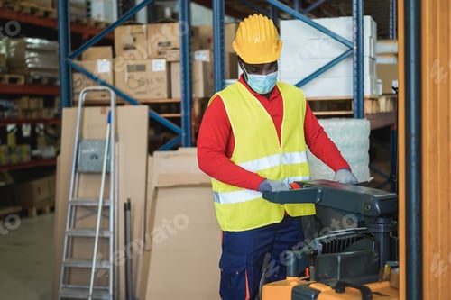 Preview: African Worker Man Pulling A Pallet Truck At Warehouse Store - Focus On Face