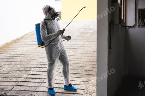 Preview: Worker In Hazmat Suit Wearing Face Mask Protection While Making Disinfection Inside City Building