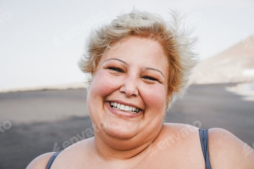 Preview: Portrait Of Curvy Woman Smiling On Camera Wearing Bikini With Beach In Background - Focus On Face