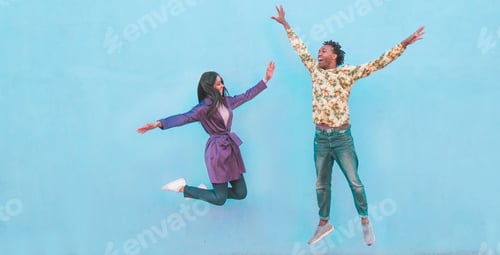 Preview: Portrait Of Black Couple Jumping Outdoor With Blue Wall In Background - Crazy Happy African Friends